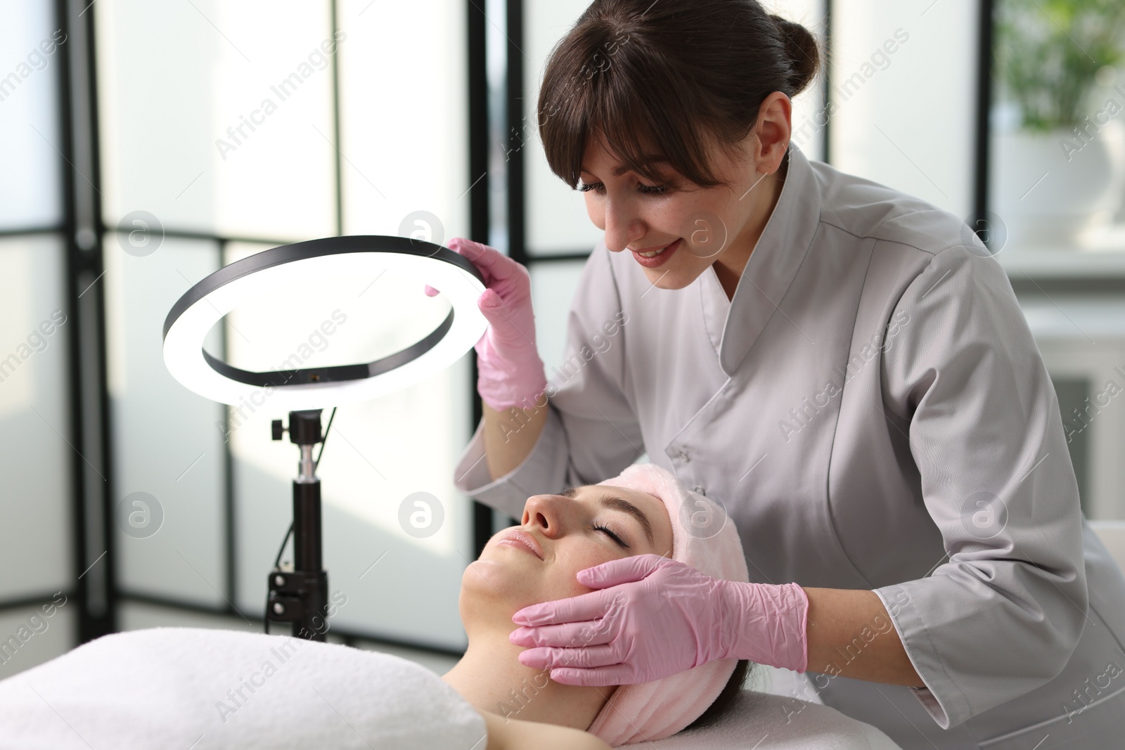 Photo of Cosmetologist making face massage to client in clinic