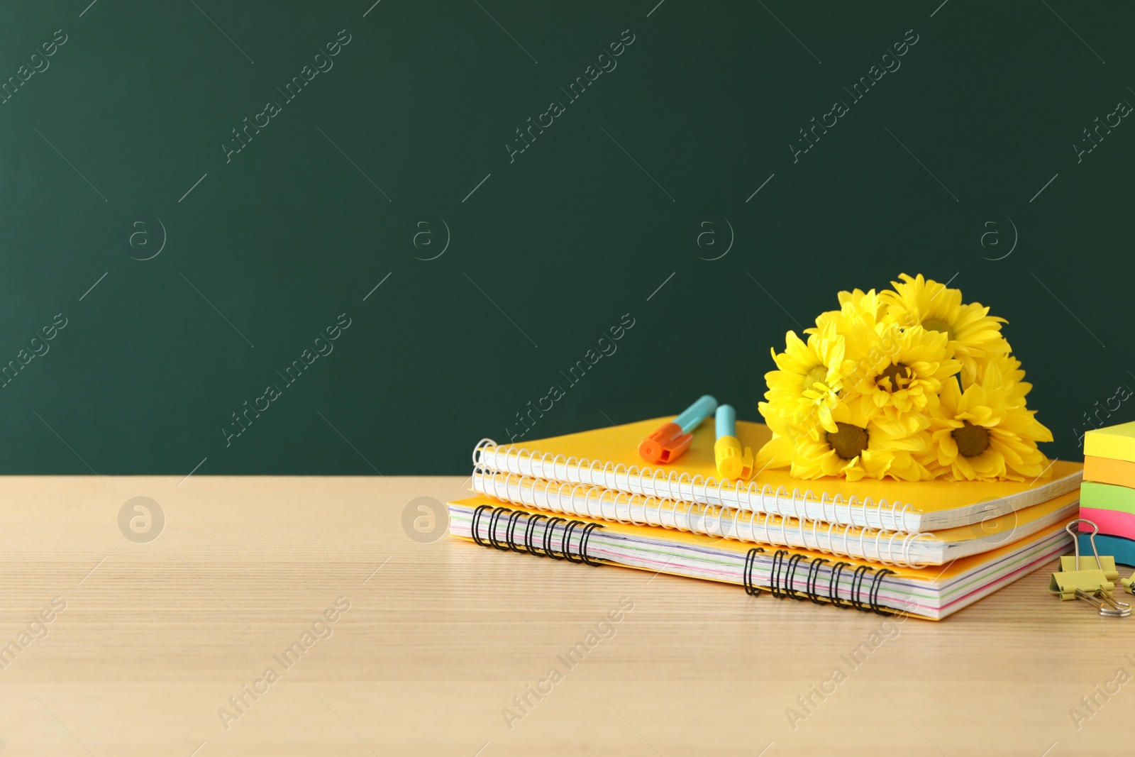 Photo of Set of stationery and flowers on wooden table near chalkboard, space for text. Teacher's Day