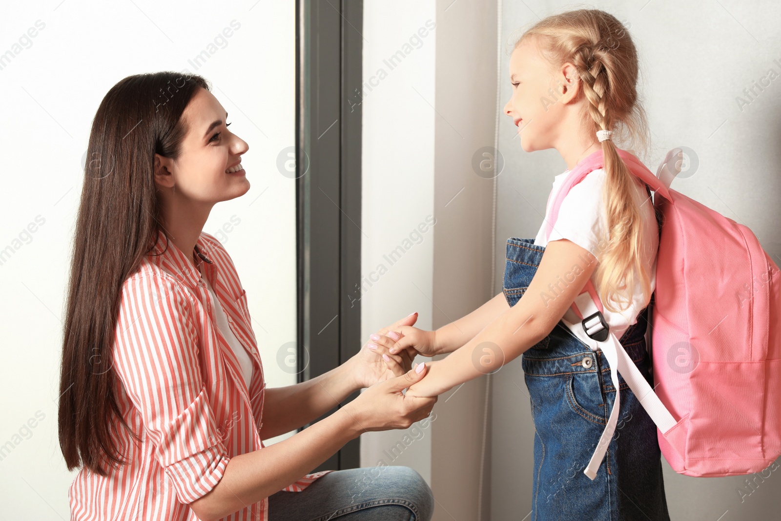 Photo of Happy mother and little child with school bag at door