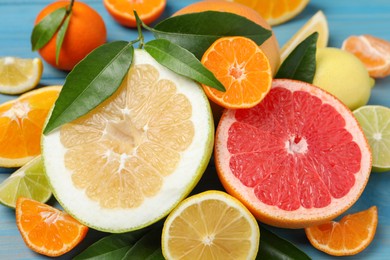 Different citrus fruits with fresh leaves on table, closeup