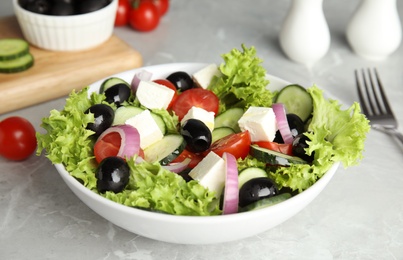 Photo of Tasty fresh Greek salad on grey marble table, closeup