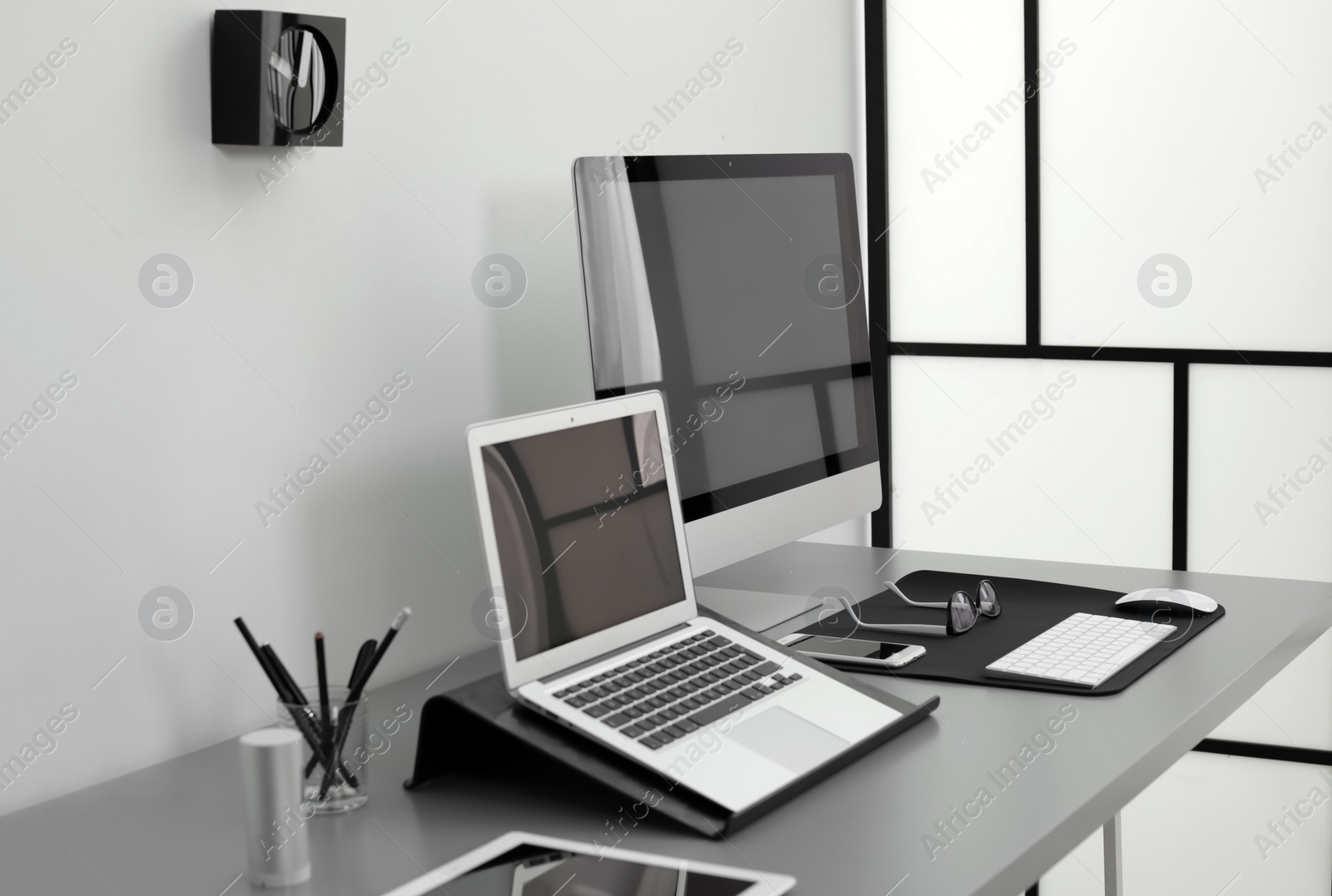 Photo of Modern workplace interior with computers on table. Space for text