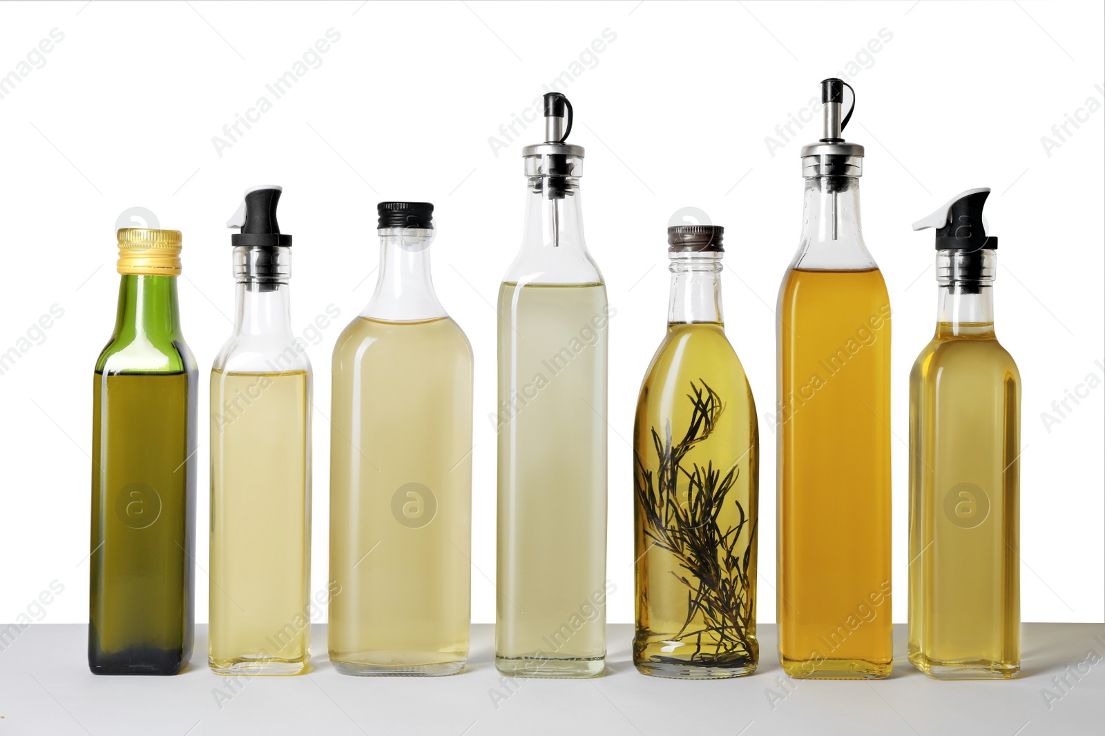 Photo of Bottles of different cooking oils on white background