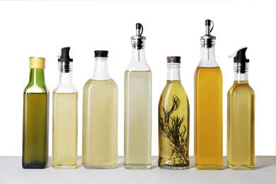Photo of Bottles of different cooking oils on white background