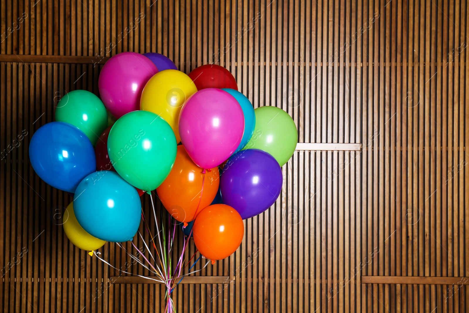 Photo of Bunch of bright balloons on wooden background with space for design