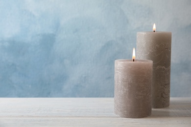 Burning candles on table against color background. Space for text