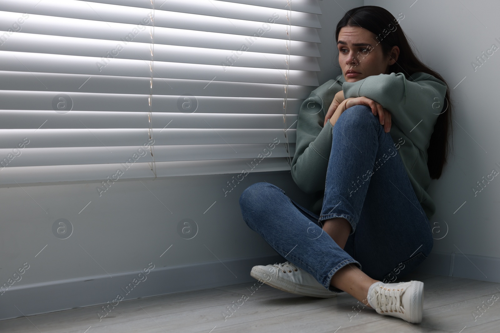 Photo of Sadness. Unhappy woman sitting on floor at home