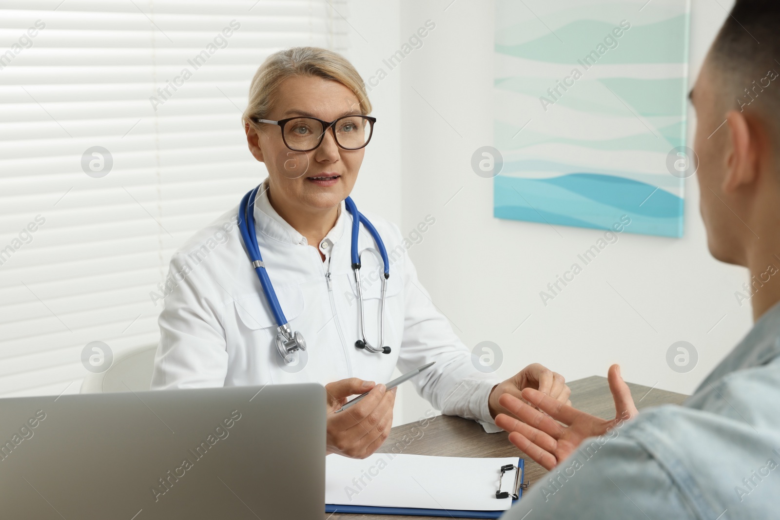 Photo of Professional doctor consulting patient at wooden table in clinic