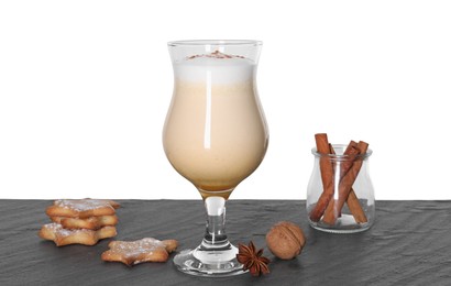 Photo of Delicious eggnog in glass, cookies and spices on grey table against white background