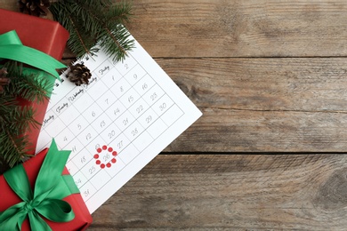 Flat lay composition with calendar and gifts on wooden table, space for text. Boxing day