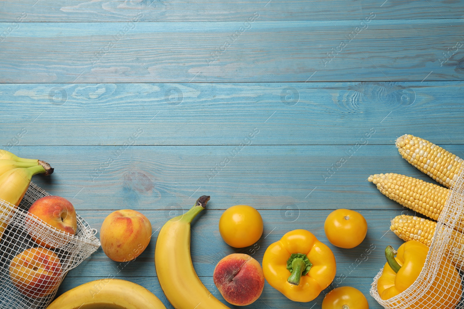 Photo of Fresh fruits and vegetables on light blue wooden table, flat lay. Space for text