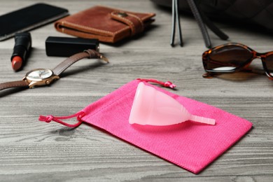 Photo of Menstrual cup and different women's accessories on wooden table