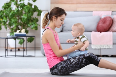 Young sportive woman doing exercise with her son at home. Fitness training