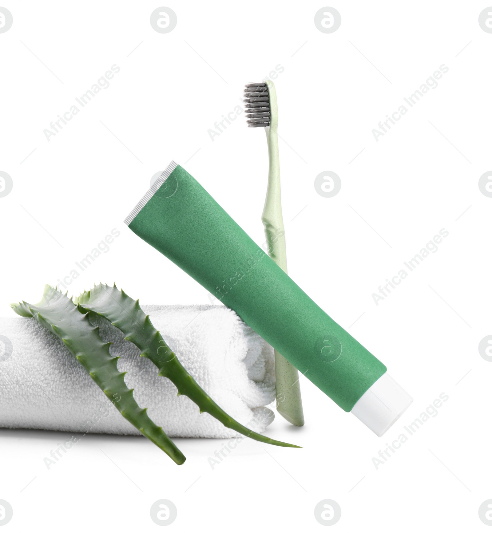 Photo of Tube of toothpaste, brush, aloe vera leaves and towel on white background