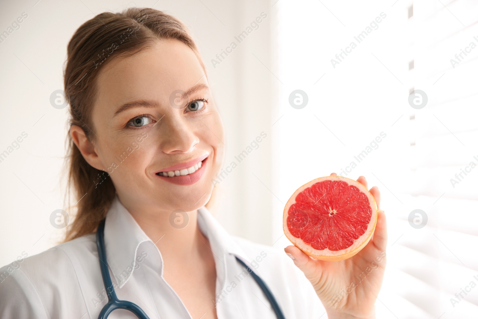 Photo of Nutritionist with grapefruit near window in office