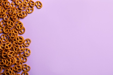 Photo of Delicious pretzel crackers on violet background, flat lay. Space for text