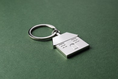 Metallic keychain in shape of house on dark green background