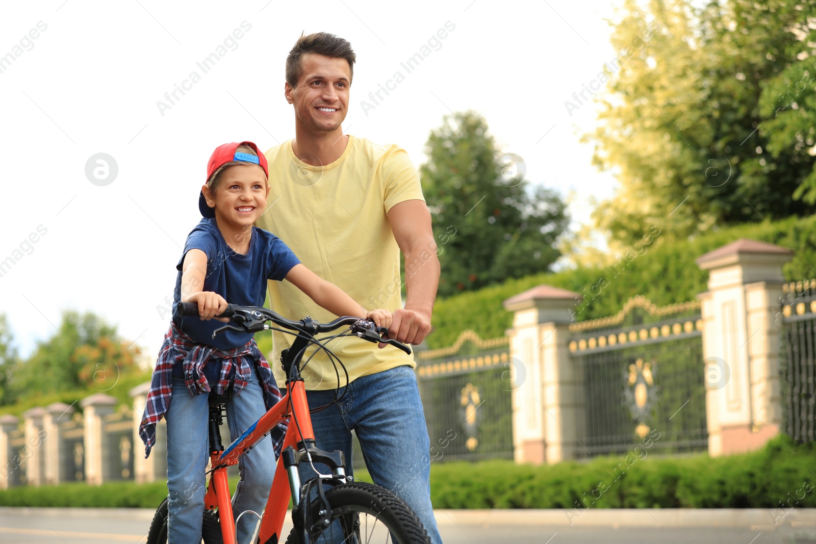 Image of Dad teaching son to ride bicycle outdoors