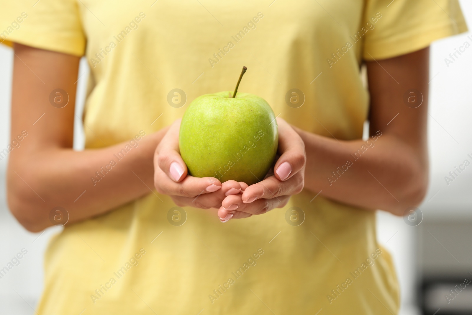 Photo of Woman holding fresh green apple indoors, closeup