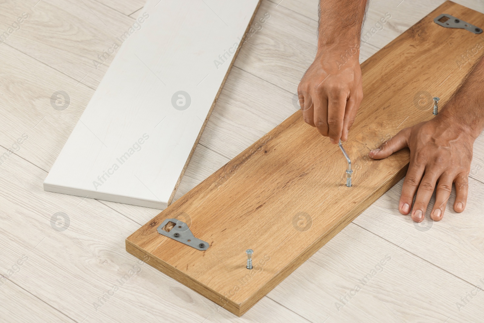 Photo of Man with hex key assembling furniture on floor, closeup