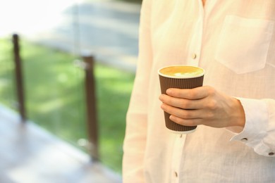 Photo of Woman holding takeaway paper cup outdoors, closeup and space for text. Coffee to go