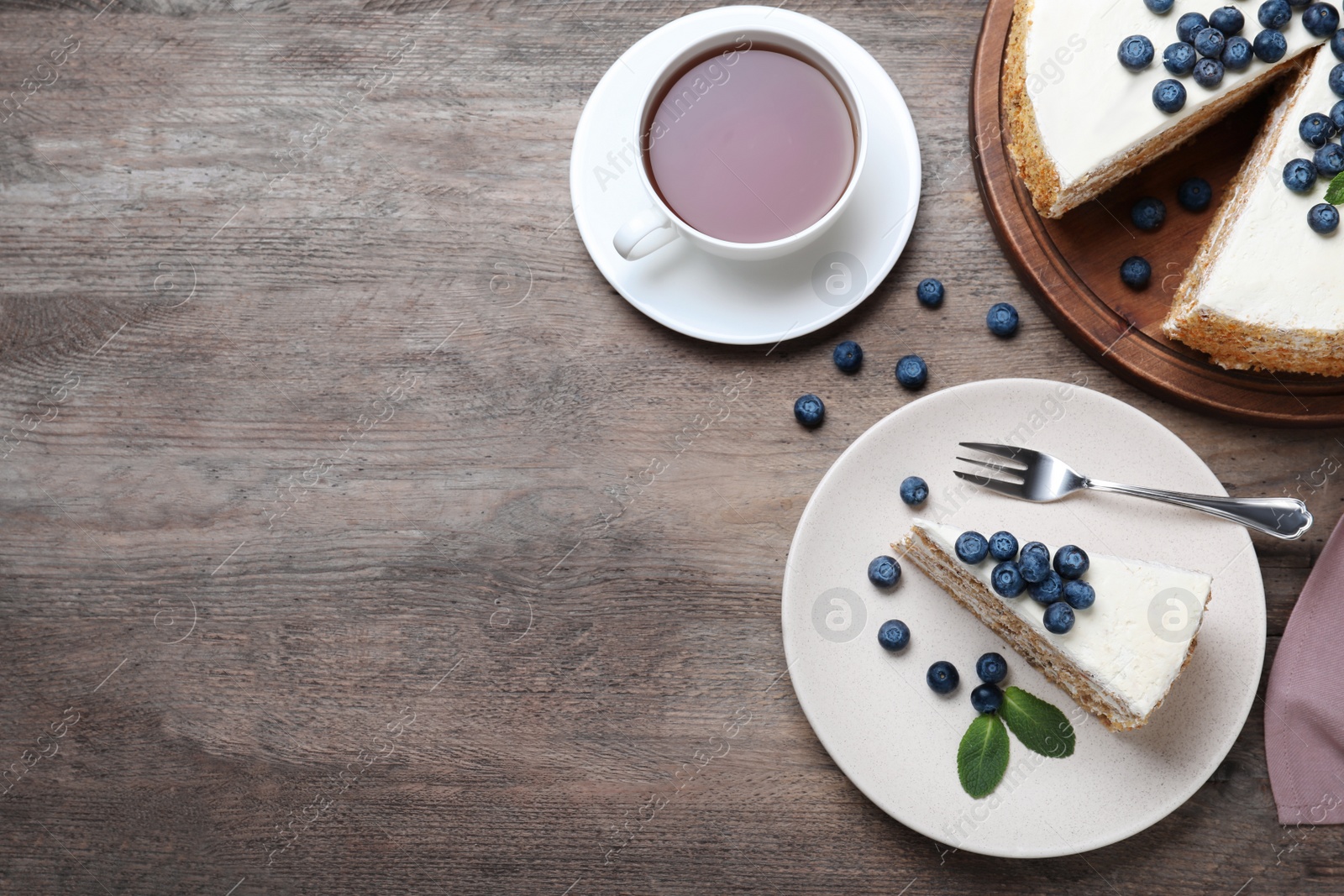 Photo of Tasty cake with berries and tea on wooden table, flat lay. Space for text