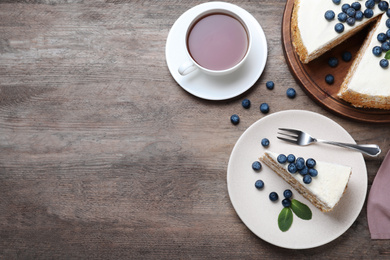 Photo of Tasty cake with berries and tea on wooden table, flat lay. Space for text