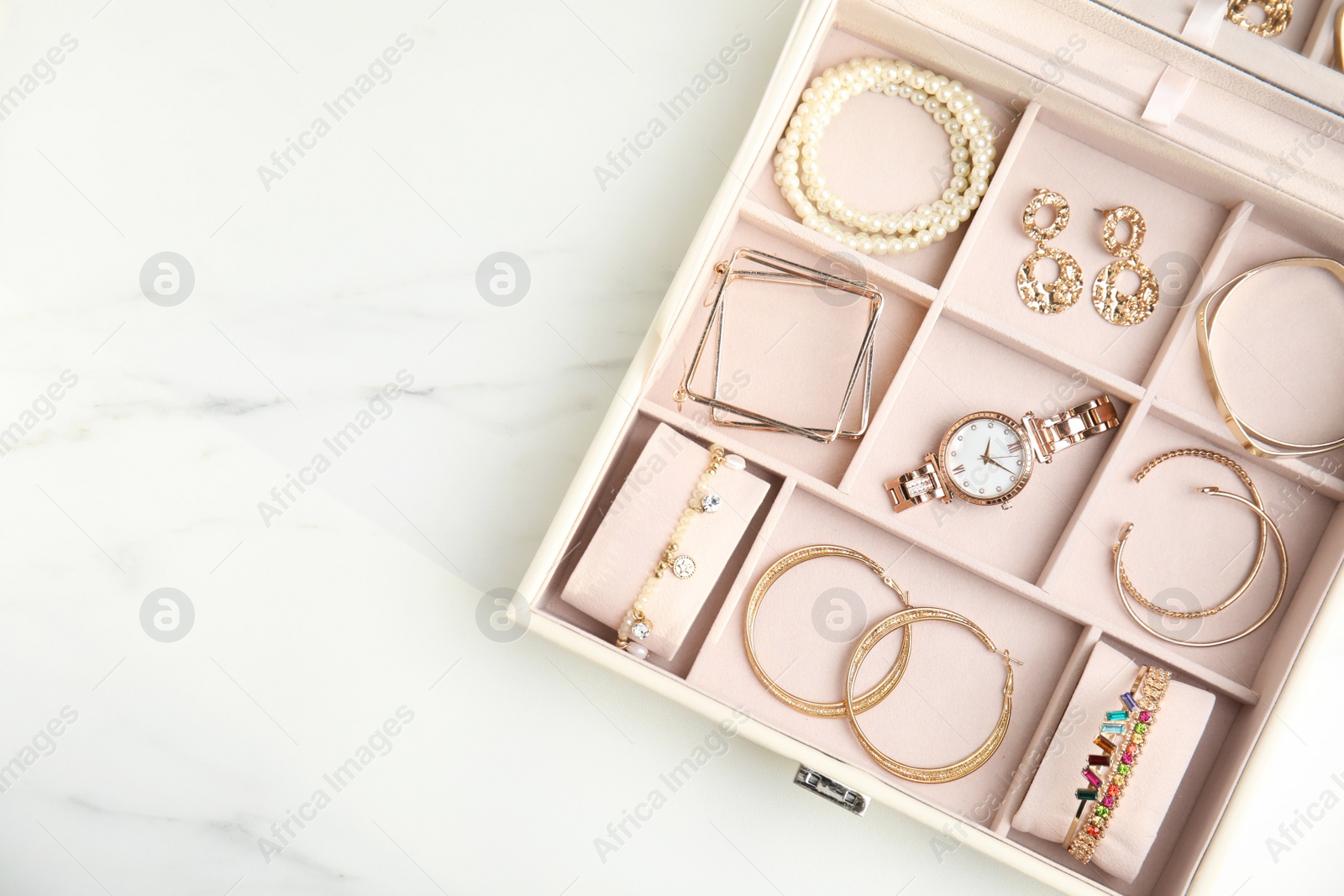 Photo of Jewelry box with stylish golden bijouterie on white marble table, top view. Space for text