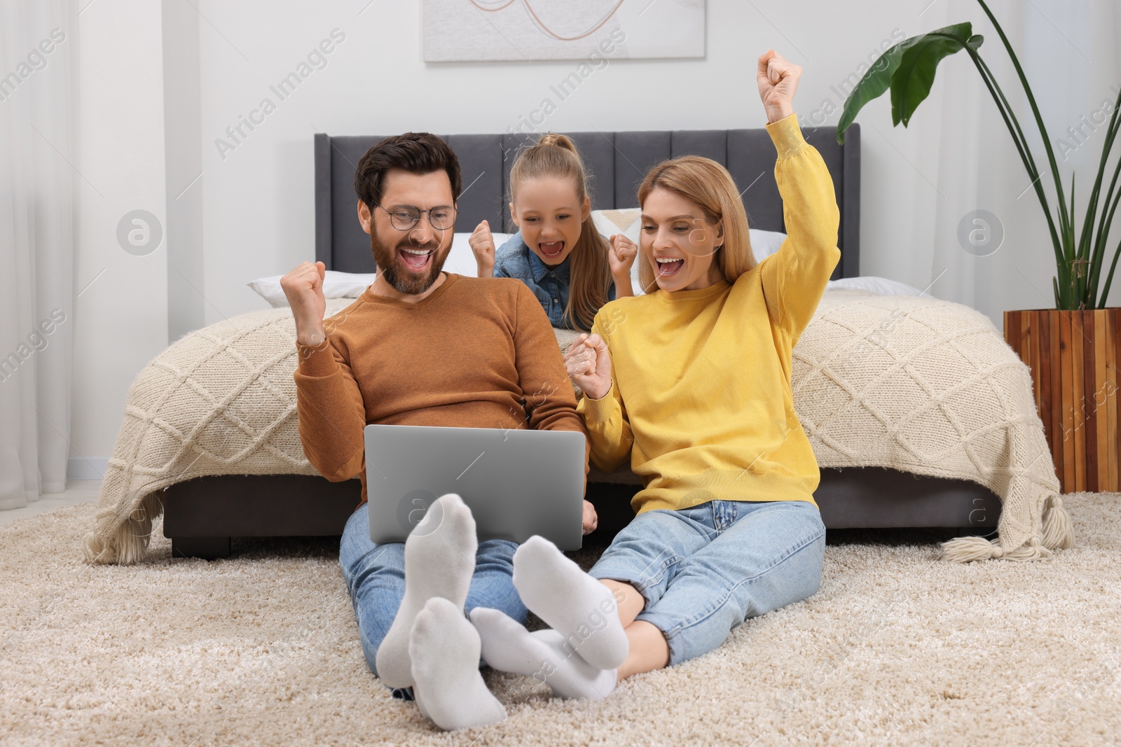 Photo of Emotional family with laptop on floor at home