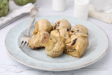 Photo of Delicious pickled artichokes served on white textured table, closeup