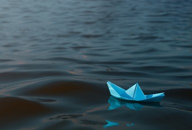 Photo of Light blue paper boat floating on river, space for text