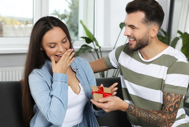 Photo of Man presenting gift to his girlfriend at home
