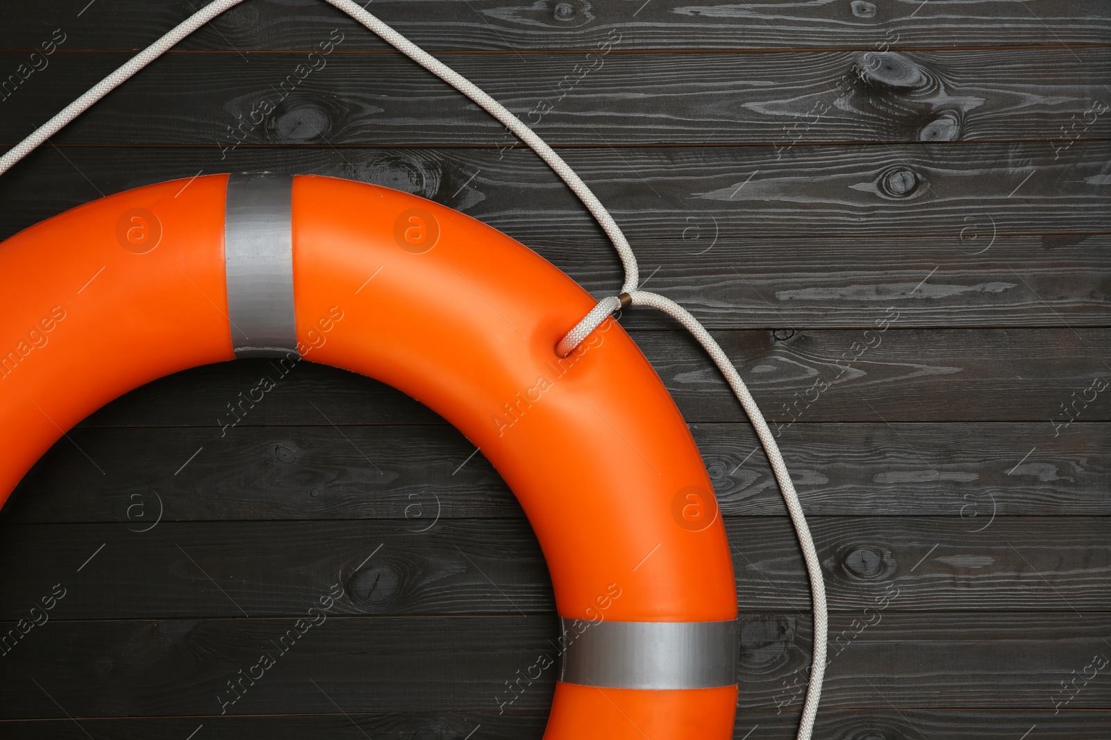 Photo of Orange lifebuoy on dark wooden background. Rescue equipment