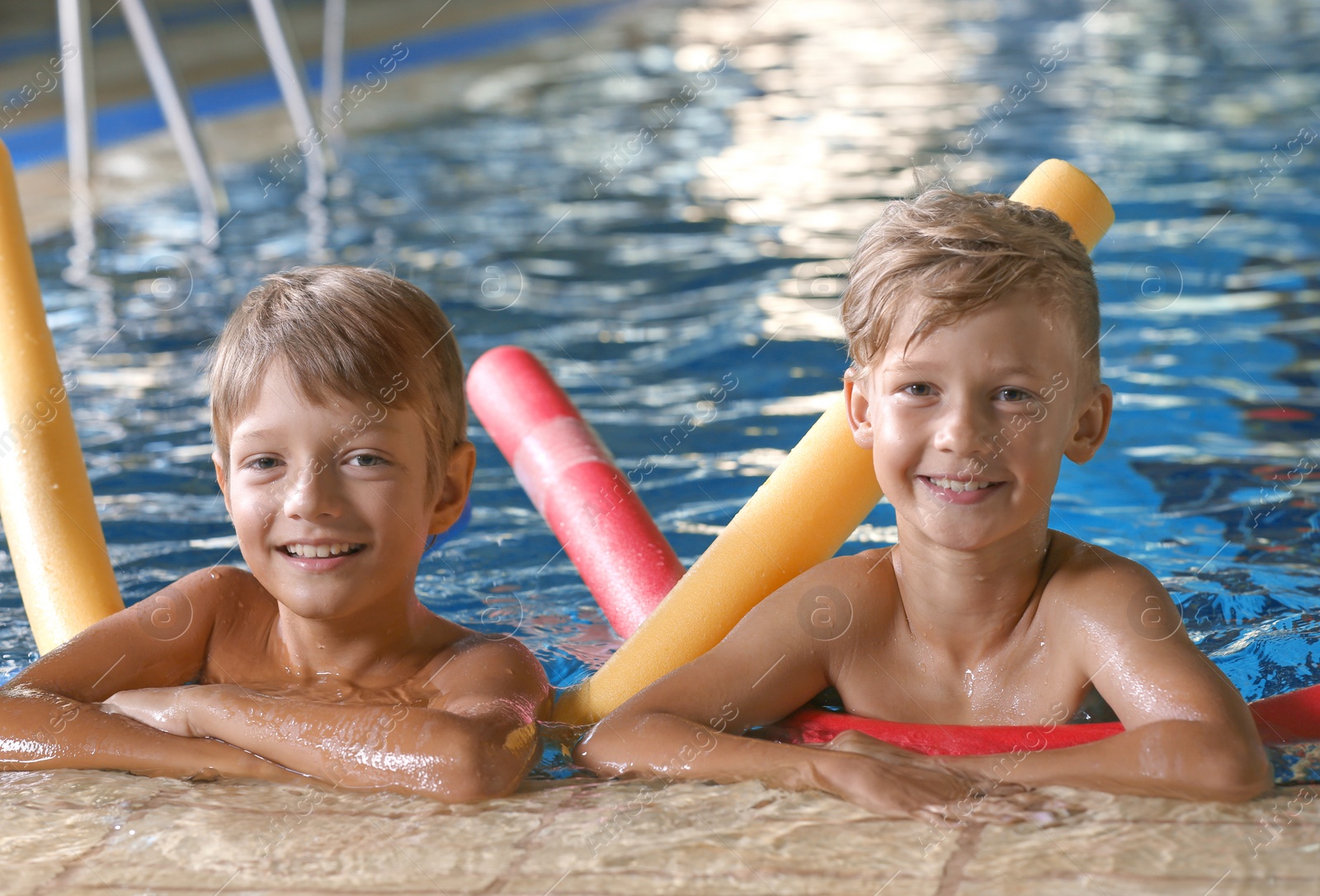 Photo of Little boys with swimming noodles in indoor pool