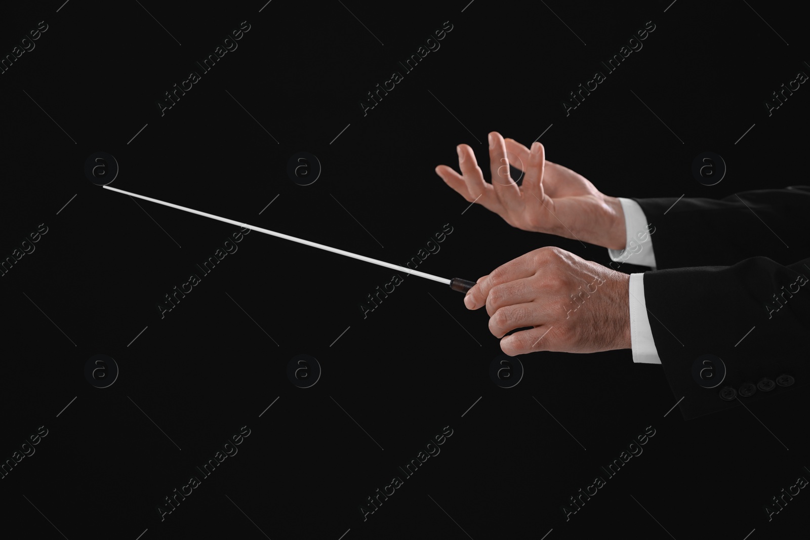 Photo of Professional conductor with baton on black background, closeup