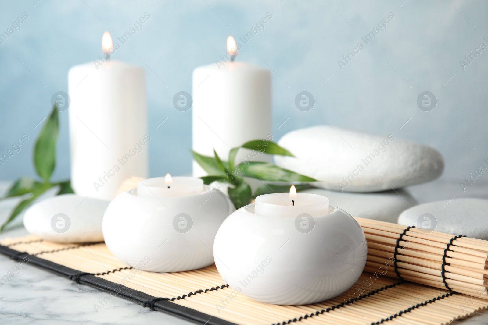 Photo of Beautiful spa composition with candles and bamboo mat on table