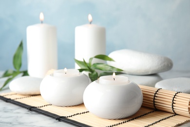 Photo of Beautiful spa composition with candles and bamboo mat on table