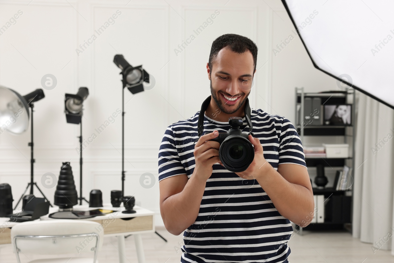 Photo of Young professional photographer with camera in modern photo studio, space for text