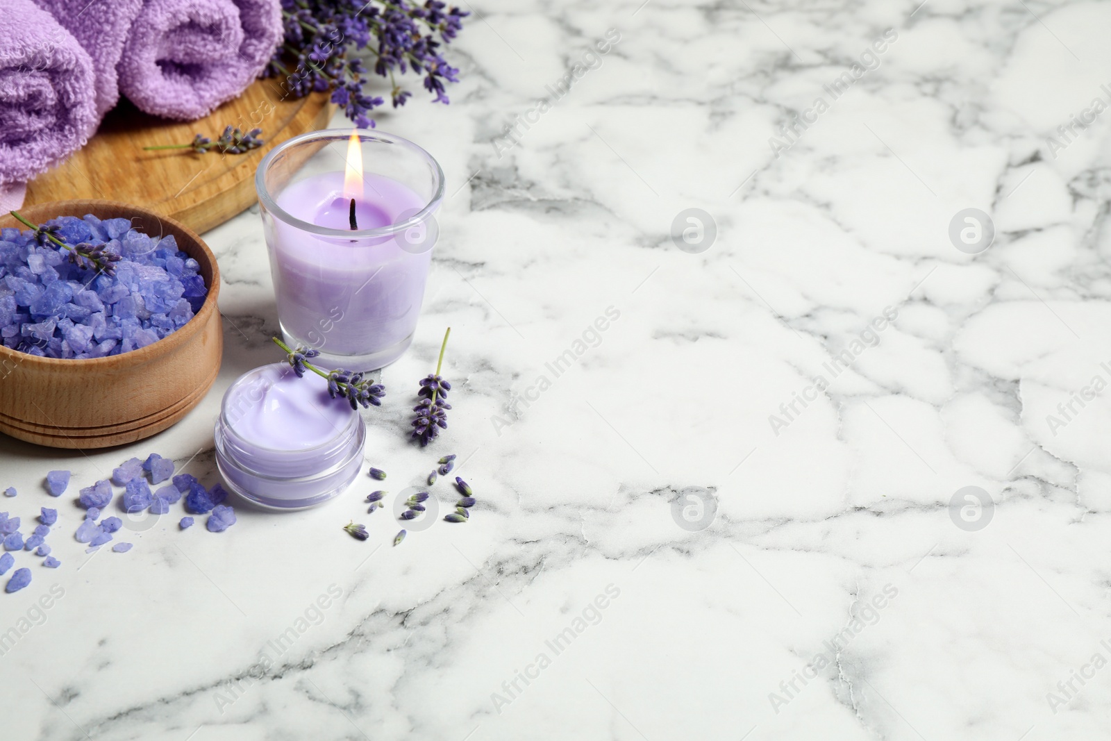 Photo of Cosmetic products and lavender flowers on white marble table. Space for text