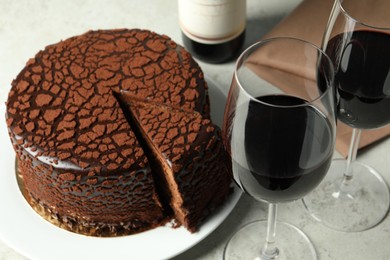 Photo of Delicious chocolate truffle cake and red wine on grey table