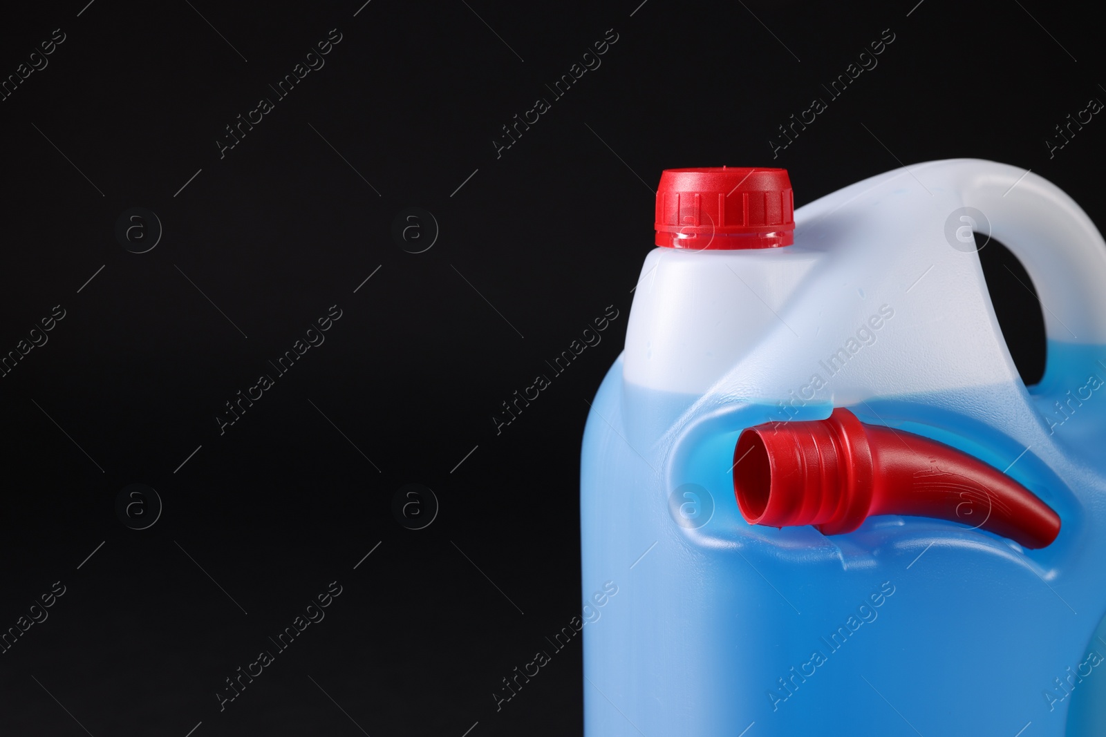 Photo of Plastic canister with blue liquid on black background, closeup. Space for text