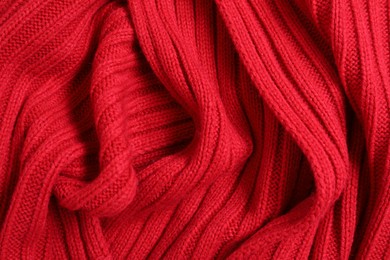 Photo of Red knitted scarf as background, top view