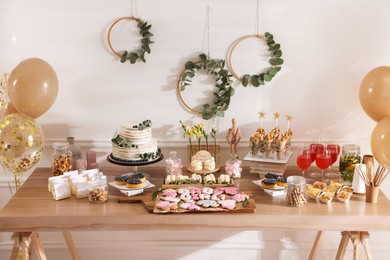 Photo of Baby shower party. Different delicious treats on wooden table indoors