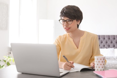 Young woman working with laptop at desk. Home office