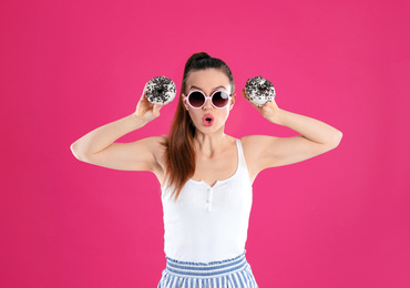 Photo of Beautiful young woman wearing sunglasses with donuts on pink background