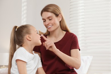 Photo of Mother applying ointment onto her daughter's nose indoors