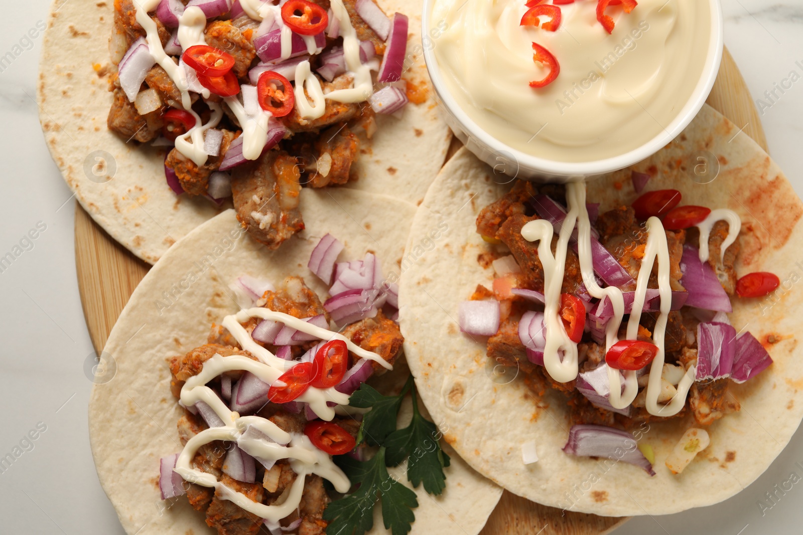 Photo of Delicious tacos with vegetables, meat and sauce on white table, top view