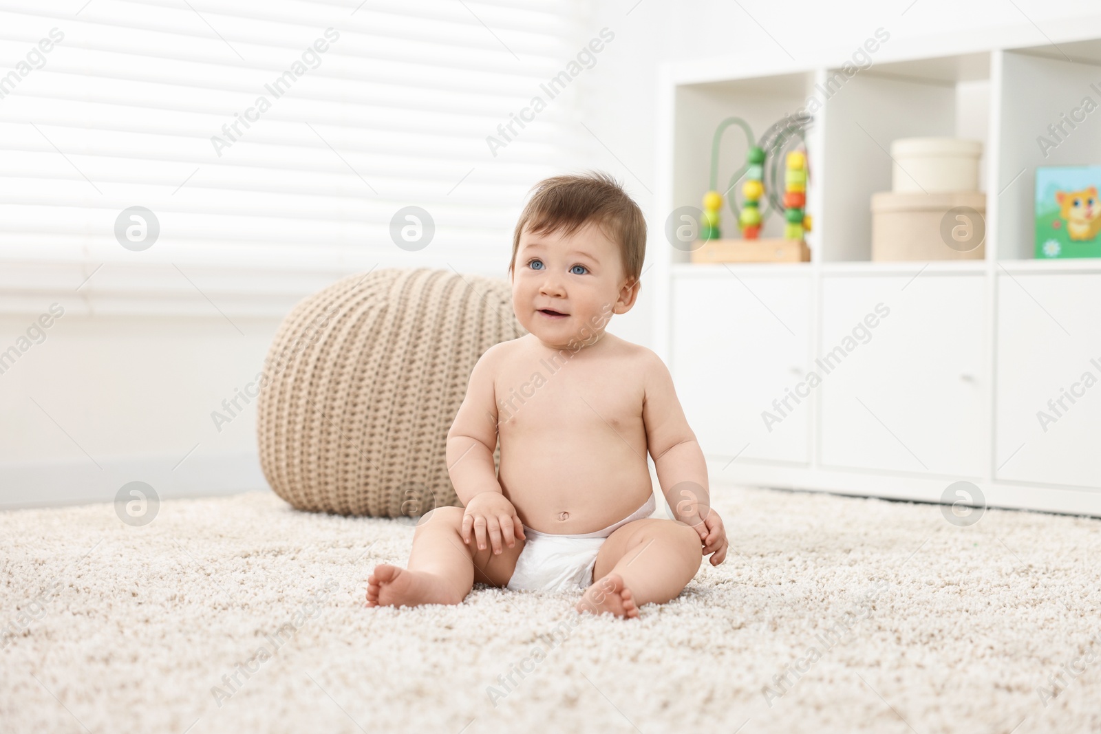 Photo of Cute baby boy sitting on carpet at home