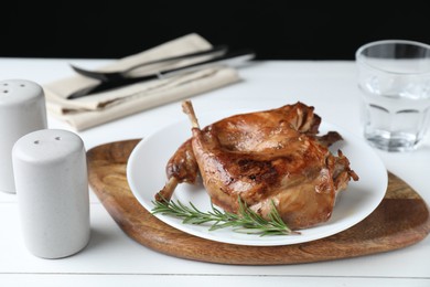 Photo of Tasty cooked rabbit meat with rosemary on white wooden table