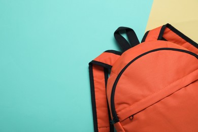 Stylish orange backpack on color background, top view. Space for text